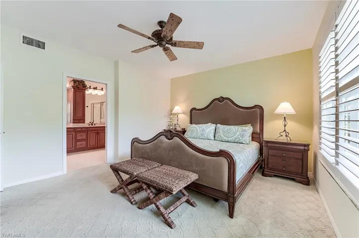 Bedroom featuring light carpet, ensuite bath, a ceiling fan, and baseboards