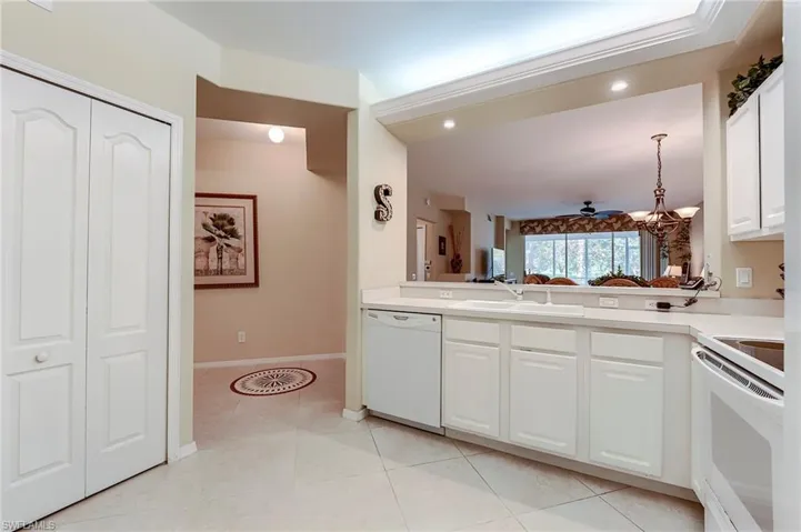 Kitchen with white appliances, a sink, white cabinetry, light countertops, and baseboards