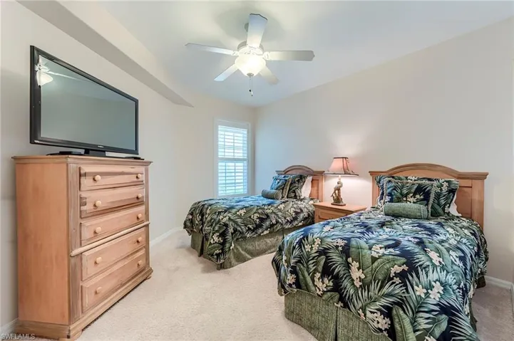 Bedroom featuring light colored carpet, baseboards, and a ceiling fan