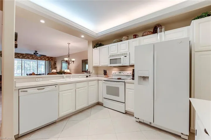Kitchen featuring white appliances, a sink, light countertops, light tile patterned floors, and a chandelier