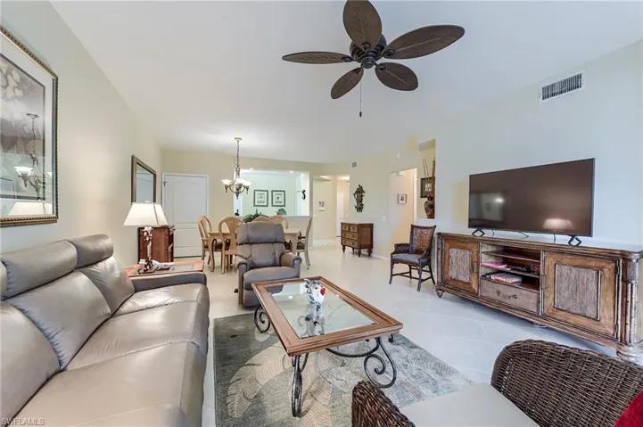 Tiled living area with a ceiling fan and a chandelier