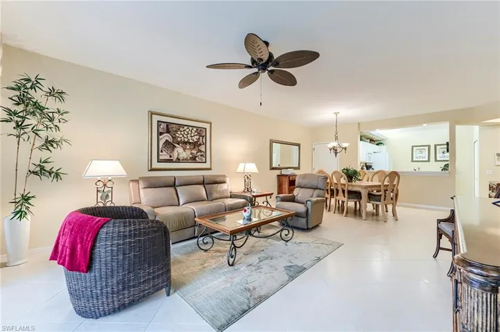 Living area with light tile patterned floors, a ceiling fan, a chandelier, and baseboards