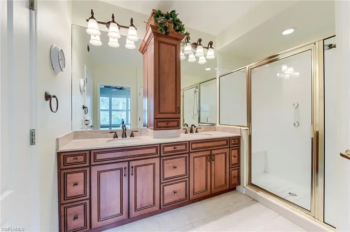 Full bath featuring a shower stall, double vanity, and tile patterned floors