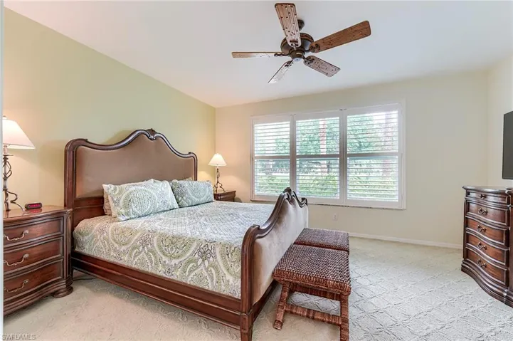 Bedroom featuring light colored carpet, a ceiling fan, and baseboards