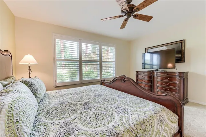 Carpeted bedroom featuring ceiling fan and baseboards