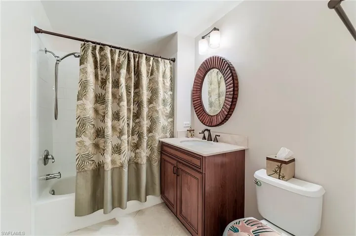 Bathroom with shower / bathtub combination with curtain, vanity, and toilet