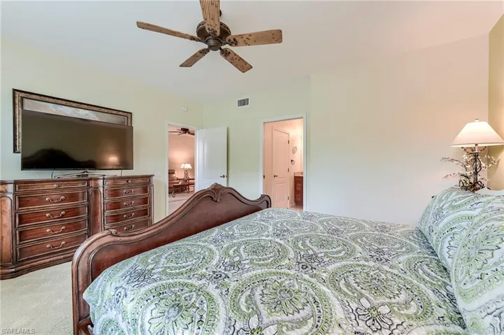Carpeted bedroom featuring a ceiling fan and ensuite bathroom