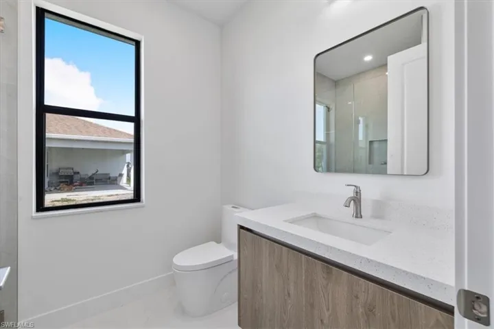 Bathroom featuring an enclosed shower, baseboards, toilet, and vanity