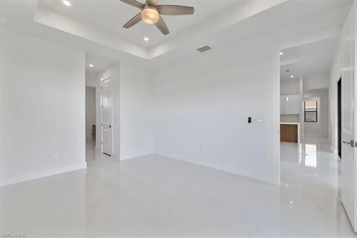 Spare room with marble finish floor, a raised ceiling, ceiling fan, and visible vents