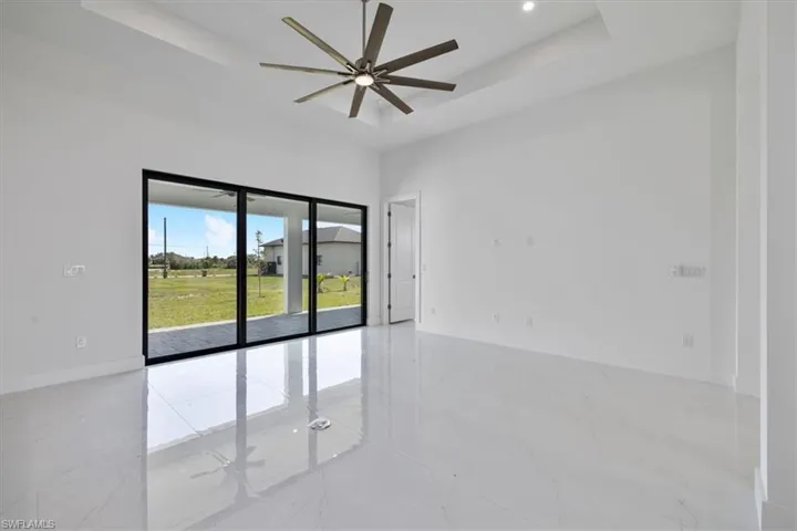 Spare room with marble finish floor, baseboards, a ceiling fan, and a raised ceiling