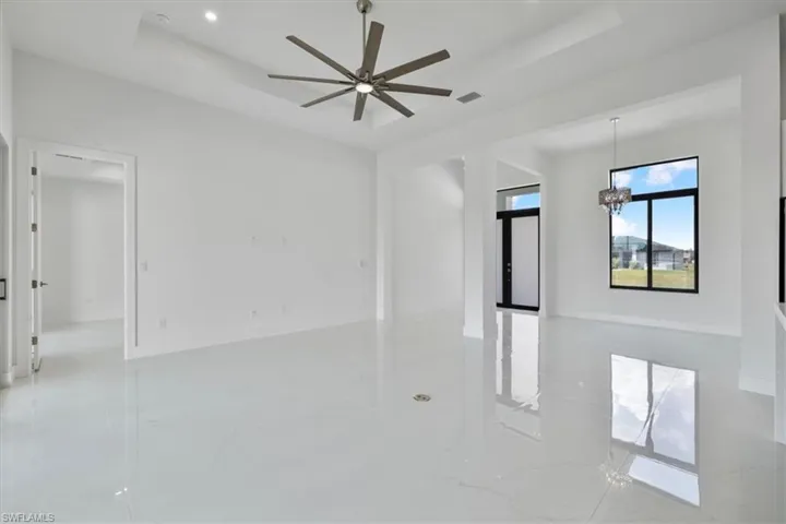 Unfurnished room featuring marble finish floor, ceiling fan with notable chandelier, visible vents, and a raised ceiling