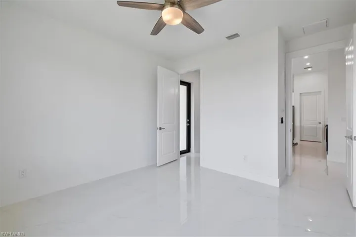 Empty room with baseboards, marble finish floor, visible vents, and a ceiling fan
