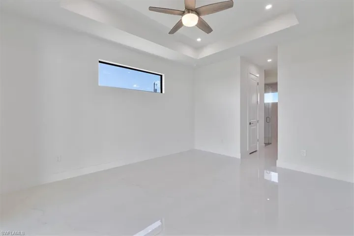 Unfurnished room with a tray ceiling, recessed lighting, baseboards, marble finish floor, and a ceiling fan