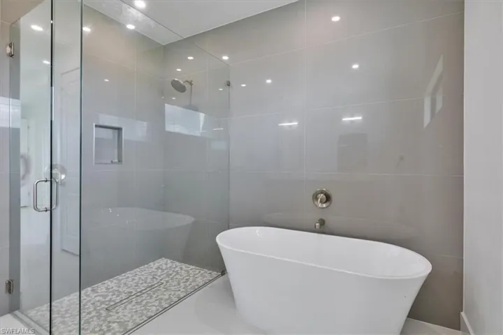 Full bath with a shower stall, a soaking tub, and tile walls