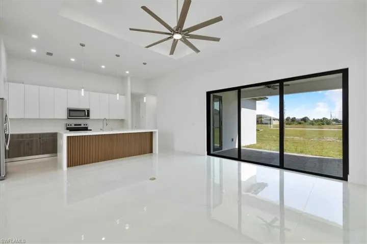 Kitchen with a ceiling fan, appliances with stainless steel finishes, modern cabinets, open floor plan, and white cabinets