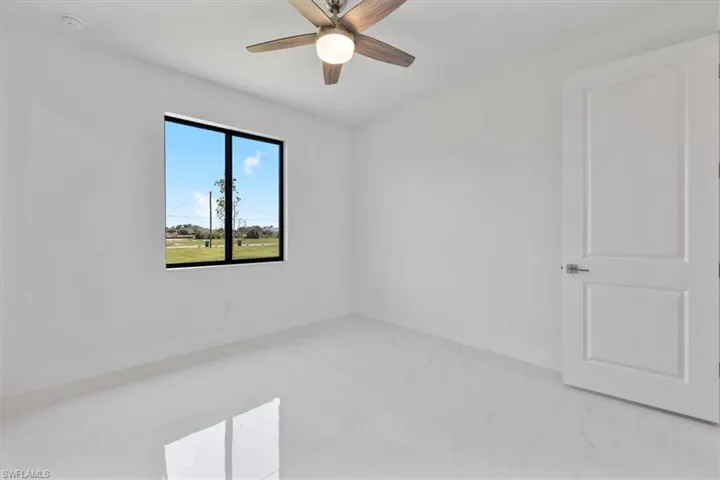 Empty room featuring marble finish floor, baseboards, and ceiling fan