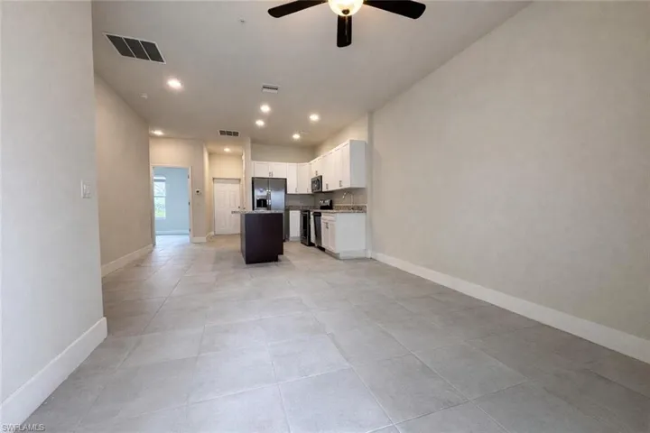 Kitchen featuring white cabinetry, a center island, a ceiling fan, open floor plan, and stainless steel appliances