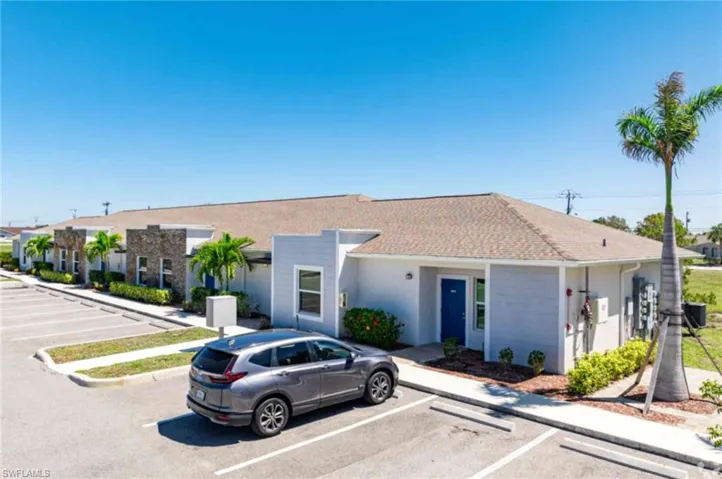 View of front of property with stucco siding and uncovered parking