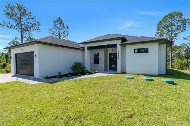 Prairie-style home with an attached garage, stucco siding, a front yard, and driveway
