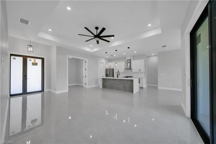 Unfurnished living room with a raised ceiling, baseboards, french doors, a ceiling fan, and recessed lighting