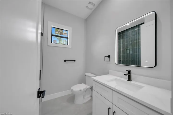 Bathroom featuring marble finish flooring, baseboards, vanity, and toilet