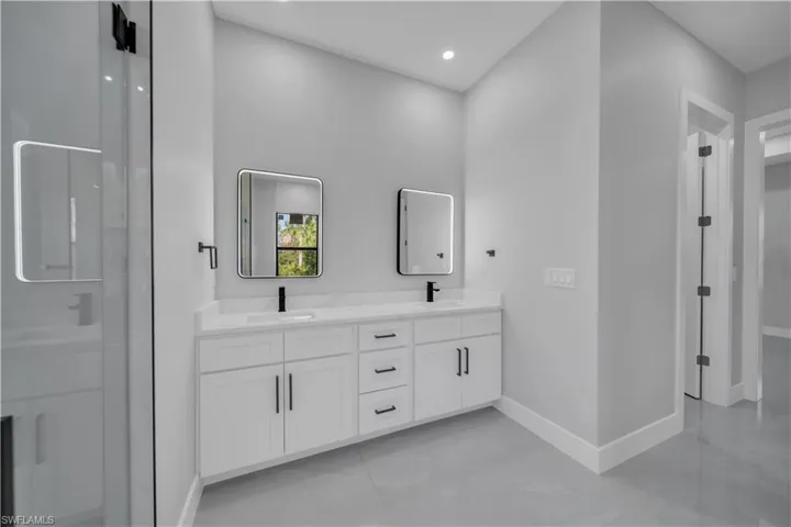 Bathroom with baseboards, double vanity, and recessed lighting