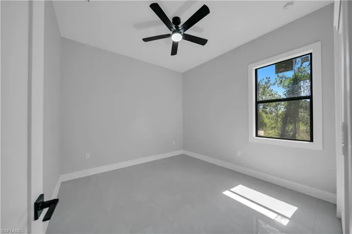 Tiled empty room with baseboards, a ceiling fan, and a smoke detector
