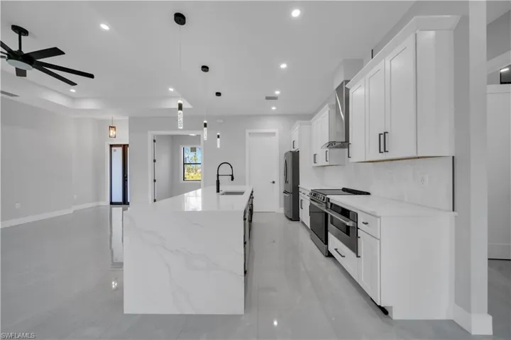 Kitchen featuring appliances with stainless steel finishes, ceiling fan, a center island with sink, white cabinetry, and recessed lighting