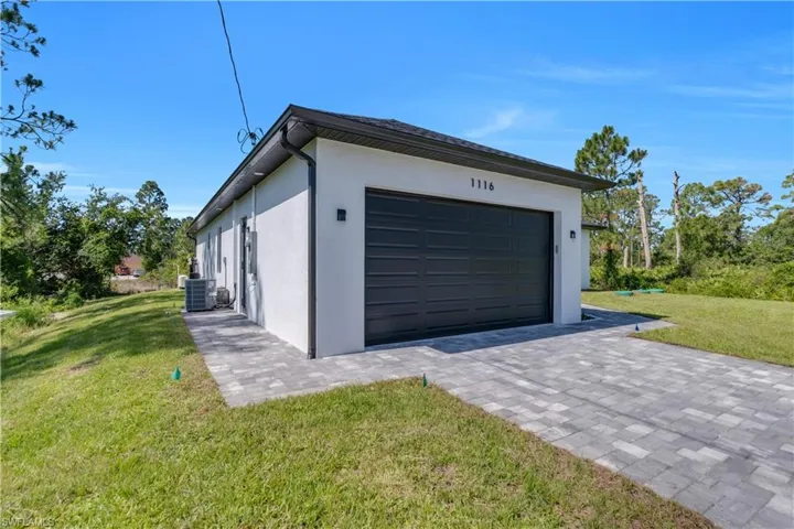 Garage featuring decorative driveway and cooling unit