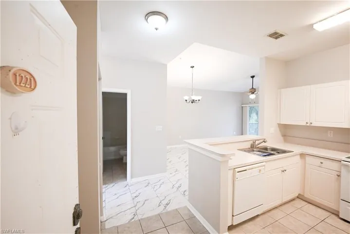 Kitchen featuring white cabinetry, a double basin sink, and a built-in dishwasher