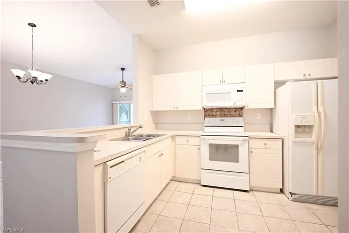 Kitchen featuring white cabinetry, a double basin stainless steel sink, a tile backsplash, and a breakfast bar