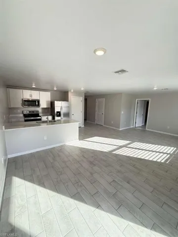 Kitchen with wood finish floors, light countertops, open floor plan, and stainless steel appliances