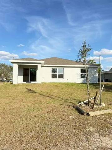 Back of house featuring stucco siding and a yard