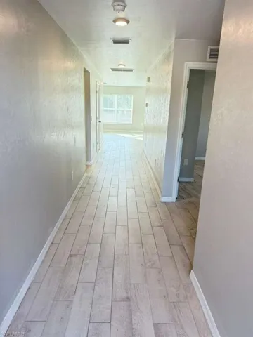 Hall with light wood-type flooring and a textured wall