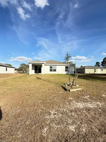 Back of property featuring a lawn and stucco siding