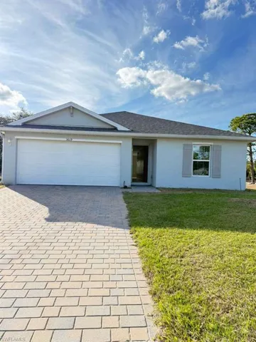 Single story home with decorative driveway, a front yard, stucco siding, and an attached garage