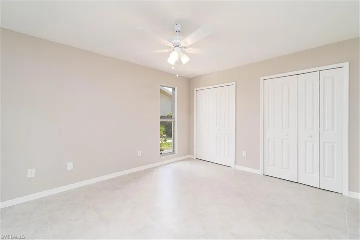 Unfurnished bedroom featuring baseboards, multiple closets, and ceiling fan