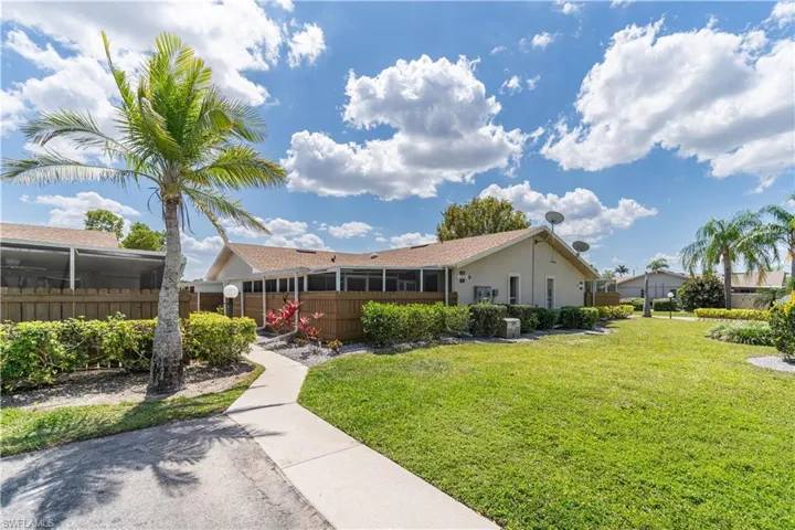 Back of property with a sunroom, fence, and a yard