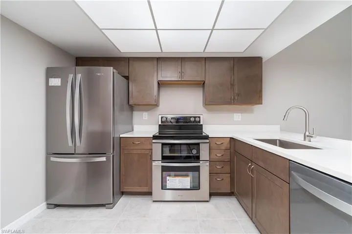 Kitchen with light tile patterned flooring, light countertops, a sink, and stainless steel appliances