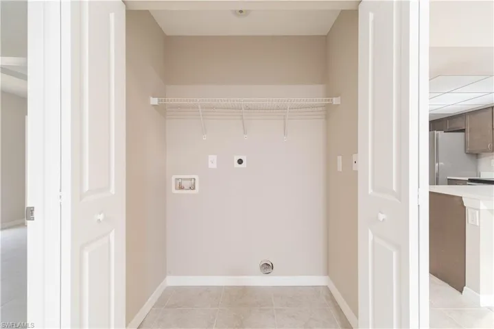 Laundry room featuring hookup for a washing machine, laundry area, light tile patterned floors, and electric dryer hookup