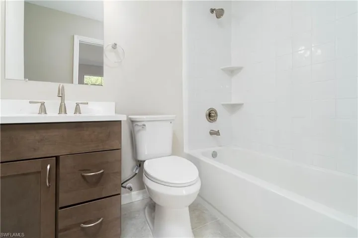 Bathroom with toilet, vanity,  shower combination, and tile patterned flooring