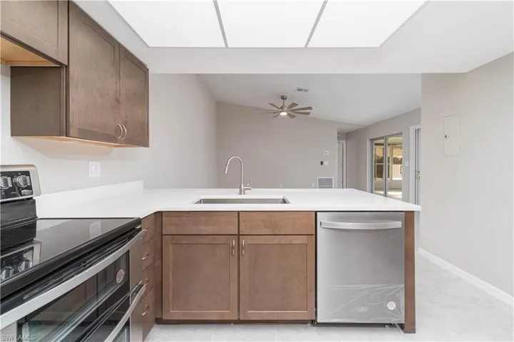 Kitchen featuring light countertops, a peninsula, a ceiling fan, appliances with stainless steel finishes, and a sink