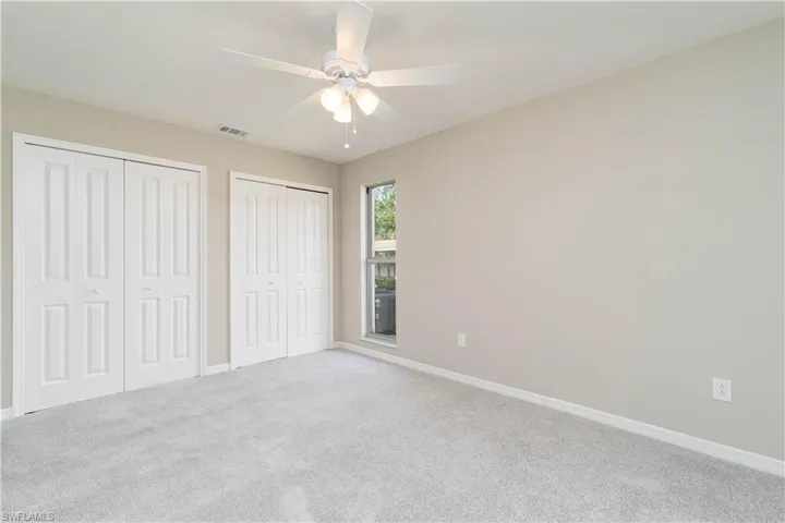 Unfurnished bedroom featuring carpet flooring, baseboards, multiple closets, ceiling fan, and visible vents