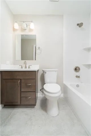 Full bath featuring toilet, bathing tub / shower combination, vanity, tile patterned flooring, and baseboards