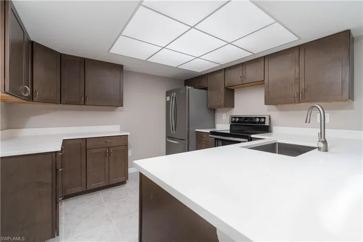 Kitchen with a sink, light countertops, appliances with stainless steel finishes, and dark brown cabinets