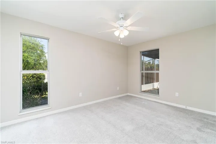 Empty room featuring baseboards, carpet floors, a wealth of natural light, and a ceiling fan