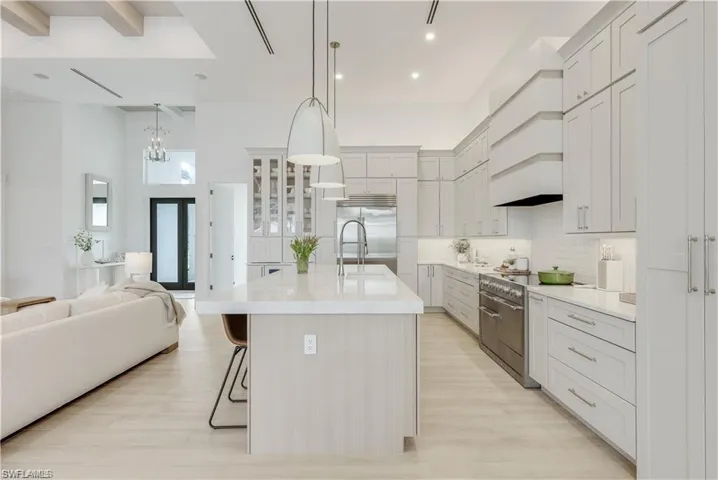 Kitchen featuring a kitchen bar, open floor plan, high quality appliances, a kitchen island with sink, and decorative light fixtures