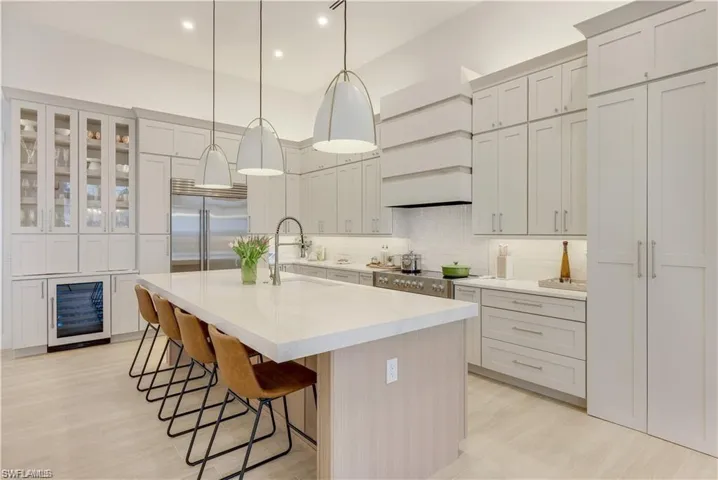 Kitchen featuring a breakfast bar, a center island with sink, light wood-style floors, stainless steel appliances, and beverage cooler