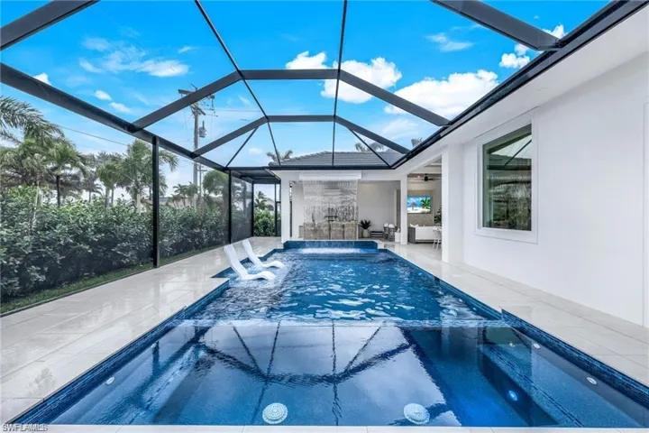 Integrated pool / hot tub with glass enclosure, a sunroom, and a patio area