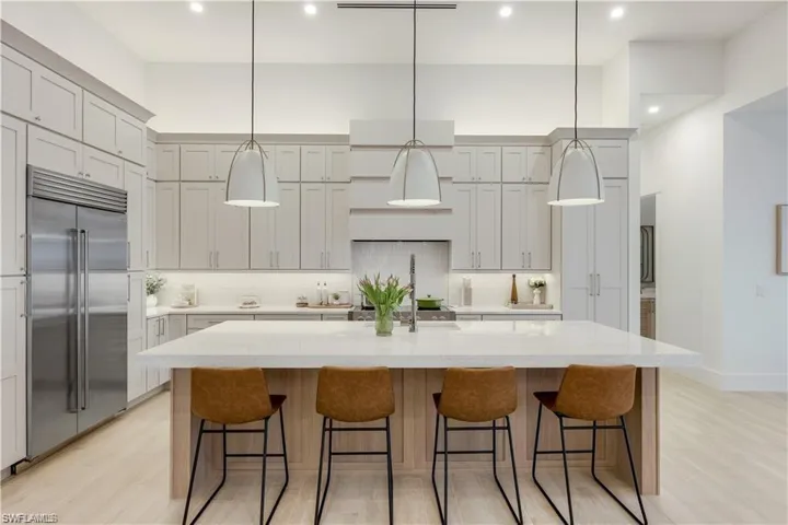 Kitchen featuring stainless steel built in fridge, a breakfast bar area, decorative light fixtures, and light wood-type flooring